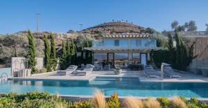 een huis met een zwembad met ligstoelen bij Marnos Luxury Villas in Kamilari