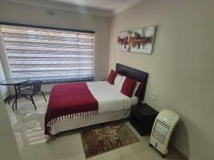 a bedroom with a bed and a table and a window at Ithonsi Guesthouse in Kempton Park