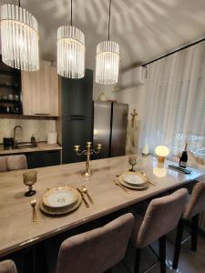 a kitchen with a dining table with chairs and chandeliers at Apartman Novska Noemi in Novska
