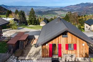 a wooden house with red doors and mountains in the background at Panorama Ferienhaus Zora in Frastanz