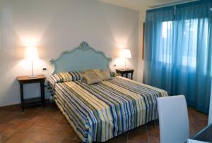 ヴェントゥリーナにあるLe Corti Del Sole Residenceのベッドルーム1室(ベッド1台、テーブル2台、ランプ2つ付)