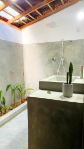 Un baño con lavabo y bañera con cactus. en Inara Stay, en Arugam Bay