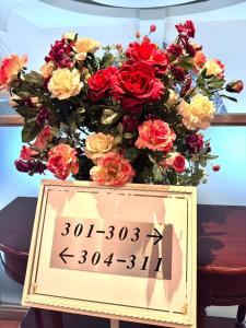 Un cartel con un ramo de flores sobre una mesa. en ホテル ルヴワール, en Izumi