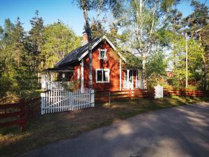 una piccola casa in legno con una recinzione bianca di Banvaktstuga anno 1905 a Fliseryd