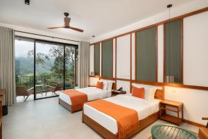 two beds in a hotel room with a balcony at Te Dalu Resort & Spa in Ella