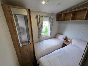 een kleine kamer met twee bedden en een raam bij Luxury 3 bed sleeps 8 caravan with sea view in Exmouth