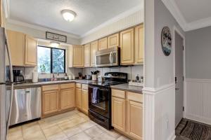 a kitchen with wooden cabinets and stainless steel appliances at Fernandina Beach Hidden Gem - Amelia Landings - 9F in Fernandina Beach