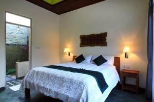 a bedroom with a large white bed with two pillows at Villa Ketut Kartika in Ubud