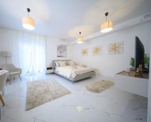 a white bedroom with a bed and a living room at Studio apartman Carera Deluxe in Vinkovci