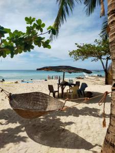 a hammock on a beach with a table and an umbrella at Diapila baybayon Sunset View in El Nido