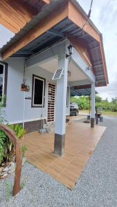 a house with a wooden patio with a roof at The Nook Housestay in Ketereh