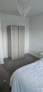 NewTown Home Host 4-5 Guests في Brettell Lane: غرفة نوم بسرير وثريا +صورة واحدة