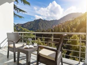 a balcony with two chairs and a table with a view at LA Riqueza Dhanolti View - Top Selling - Award Winning Hotel - Mountain View Rooms - Parking on site - Lift - Near to Eco Park & Surkanda Devi Temple in Dhanaulti