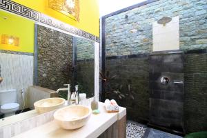 a bathroom with two sinks and a stone wall at Villa Ketut Kartika in Ubud +30 photos