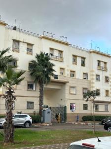 a large building with a palm tree in front of it at Séjour Confort clim Navette Aéroport in Salé