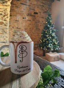 Borgo del Canto - Traditional Country Retreat - 30 Min from the Sea! في Borghetto dʼArroscia: فنجان قهوة موضوع على طاولة عليها شجرة عيد الميلاد