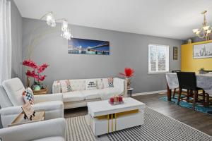 ein Wohnzimmer mit einer weißen Couch und einem Tisch in der Unterkunft Bright 4BR Near MSU & Downtown home in Packard