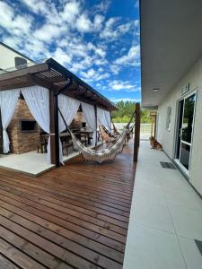 eine Holzterrasse mit einer Hängematte auf einem Haus in der Unterkunft Pousada Aloha Pinheira in Palhoça