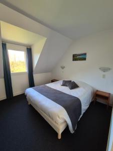 a bedroom with a large white bed with a window at La Roche du Marais in Omonville-la-Petite
