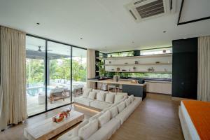 een woonkamer met witte meubels en een groot raam bij Villa Zeno Arete Pererenan 6 Bedroom , Ice Bath, Sauna and Gym in Tumbak Bayuh