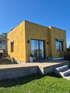 una casa amarilla con puertas de cristal y escaleras en Cabaña La Resolana, en Tandil