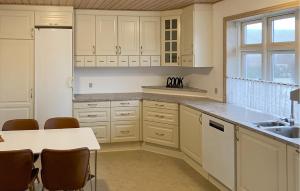 a kitchen with white cabinets and a table with chairs at 5 Bedroom Awesome Home In Lemvig in Nørby