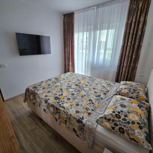 a bedroom with a bed with a blanket and a window at Downtown City Apartment in Râmnicu Vâlcea