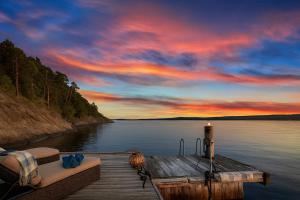 a dock on a lake with a sunset at Waterfront Cabin - 15 Minutes from Downtown Oslo in Oslo +4 photos
