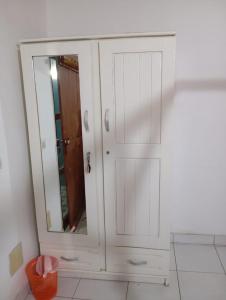 a white cabinet with a mirror in a room at Chambre d'hôte in Lomé