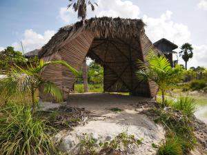- un petit bâtiment avec un toit de chaume sur une plage dans l'établissement Chalé na Lagoa, à Guriú