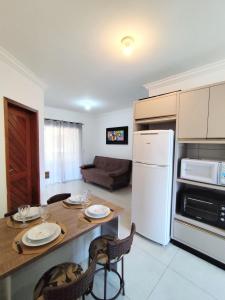 Residencial Ernesto Neves - 5 min da praia de Bombas في بومبينهاس: مطبخ وغرفة معيشة مع طاولة وكراسي