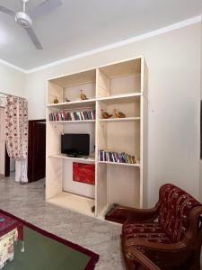 a living room with a book shelf with a tv at Abdalla's House in Al Aqālitah
