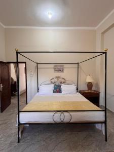 a bed with a black frame and white pillows at Abdalla's House in Al Aqālitah