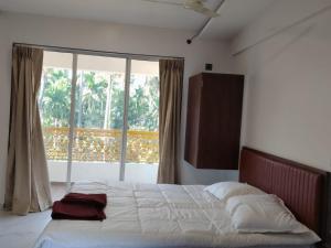 uma cama num quarto com uma grande janela em Hare Krishna Beach Resort em Srīvardhan mais 22 fotografias