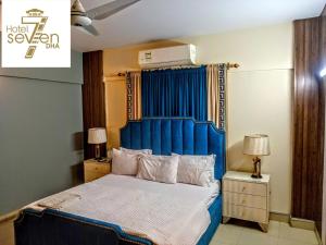 a bed with a blue headboard in a bedroom at Hotel 7 DHA in Karachi