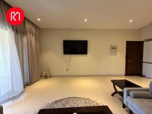 Una sala de estar con un sofá y un televisor en la pared. en Luxurious Golf and Sea View 2 Bedroom Apartment, en As Sīfah