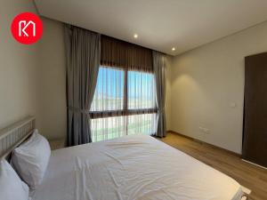 Un dormitorio con una cama y una ventana grande. en Luxurious Golf and Sea View 2 Bedroom Apartment, en As Sīfah