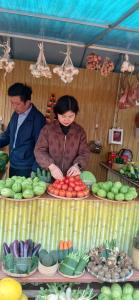 zwei Frauen, die hinter einem Tisch aus Obst und Gemüse stehen in der Unterkunft datanithanh homestay Mộc châu in Làng Môn