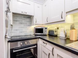 een keuken met witte kasten en een magnetron bij Pebble Cottage - Uk32243 in Aberdyfi +10 foto's