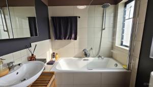 um banheiro com uma grande banheira branca e uma pia em Oceans Deep at Lagoon Terrace - Knysna! em Knysna mais 4 fotografias