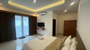 een slaapkamer met een groot bed en een televisie bij Honeymoon Villa canggu in Sempidi +17 foto's