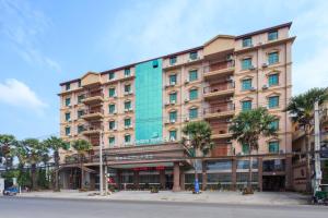 a large building with palm trees in front of it at Rose Garden International Hotel in Phnom Penh