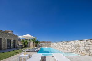 a swimming pool with chairs and an umbrella next to a building at Thalmargia Villas, with Pool, Hot Tub & Ultimate Peace, By ThinkVilla in Garazo +125 photos