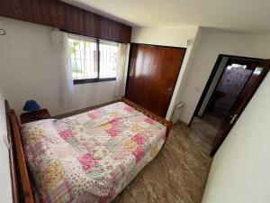 een slaapkamer met een bed met een dekbed erop bij Chalet del Sur in Villa Gesell