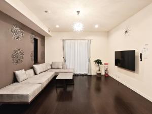 Una sala de estar con un sofá y un televisor. en Osaka Lodge Midori - Designer House by Mitsui Home, en Sakai