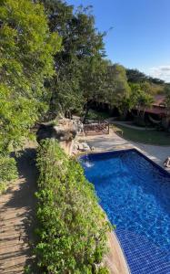 a swimming pool in a yard next to trees at Pousada Meraki in Serra do Cipo