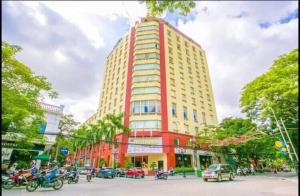 ein hohes rot-gelbes Gebäude an einer Stadtstraße in der Unterkunft DG Tower in Haiphong