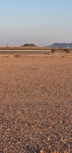 an empty field with three pens in the distance at مخيم السراي الشتوي in ‘Ibrī