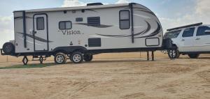 a camper parked next to a van in the desert at مخيم السراي الشتوي in ‘Ibrī