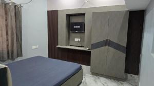 een kamer met een bed en een kast met een tv bij Deoghar BnB Homestay in Deoghar